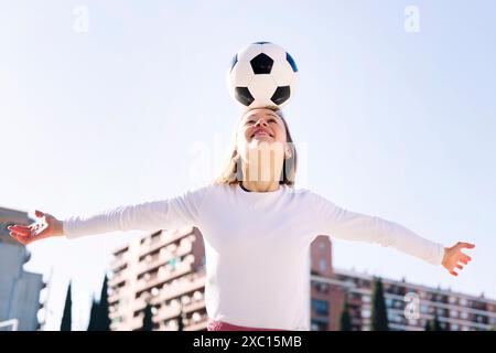 testa di donna caucasica sorridente che tocca il pallone da calcio Foto Stock