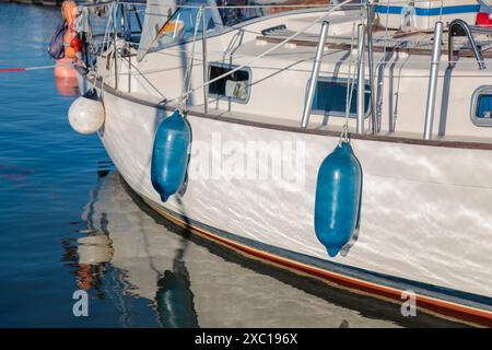 Barca ormeggiata con parafanghi blu appesi accanto all'imbarcazione, estate soleggiata, barca a vela, protezione yacht in Finlandia Foto Stock