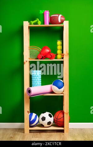 Ripiani con diverse attrezzature sportive contro il muro verde Foto Stock