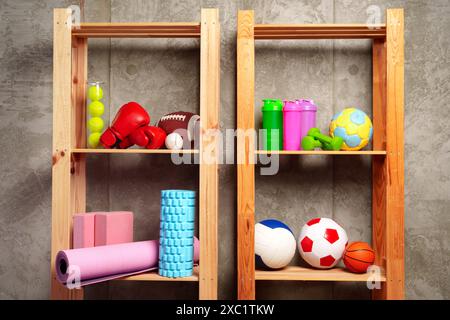 Ripiani con diverse attrezzature sportive contro il muro verde Foto Stock