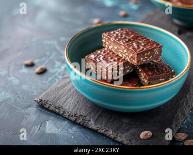 Foto del cibo dei bar Nanaimo in una moderna ciotola ciano in ceramica posta su un tavolo di ardesia scuro Foto Stock