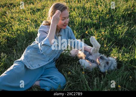 la giovane donna con un cane senza razza è sdraiata sull'erba Foto Stock