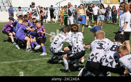 ODESSA, UCRAINA, 9 giugno 2024: Squadre per bambini giocano a tiro di guerra al festival sportivo. Lotta di squadra sportiva - tiro alla fune sull'erba verde del prato dello stadio. Chi Foto Stock