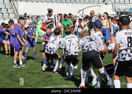 ODESSA, UCRAINA, 9 giugno 2024: Squadre per bambini giocano a tiro di guerra al festival sportivo. Lotta di squadra sportiva - tiro alla fune sull'erba verde del prato dello stadio. Chi Foto Stock