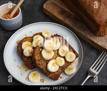 Toast alla francese con pane alla banana ricoperto di fette di banana fresche e miele Foto Stock