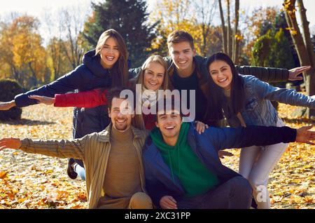 Gli amici sorridenti in giacche e sciarpe posano per scattare foto, abbracciano e allargano le braccia ai lati. Foto Stock