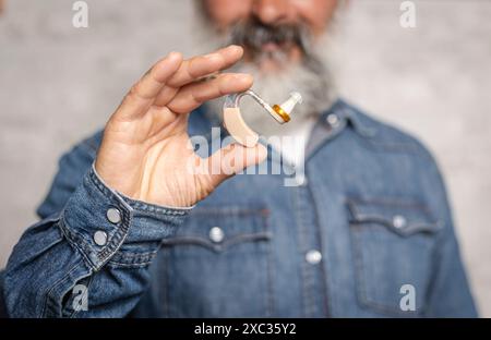 Primo piano di un anziano con un apparecchio acustico, sottolineando la salute e la tecnologia dell'udito. Foto Stock