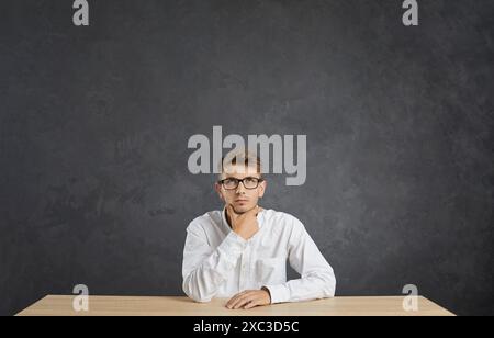 Ritratto di serio giovane uomo caucasico con espressione pensiva su sfondo grigio. Foto Stock