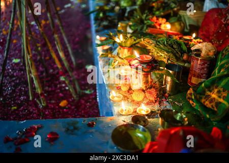 tradizionali offerte sacre di lampade a olio in fiamme sul lato del fiume durante il festival chhath da parte di un devoto Foto Stock