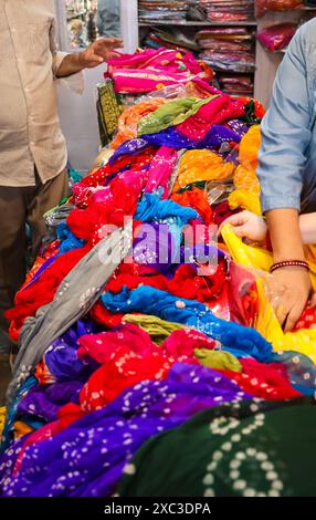 al dettaglio il venditore mostra diversi tipi di abiti tradizionali indiani sari al cliente in negozio Foto Stock