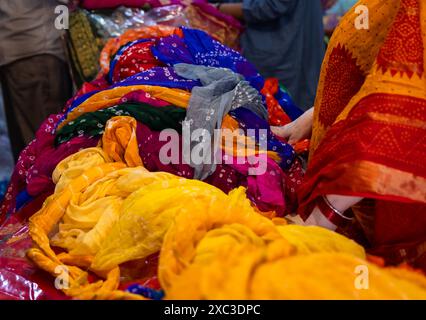 al dettaglio il venditore mostra diversi tipi di abiti tradizionali indiani sari al cliente in negozio Foto Stock