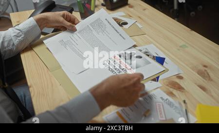 Un uomo esamina i documenti delle indagini su una scrivania con prove, foto e rapporti. Foto Stock