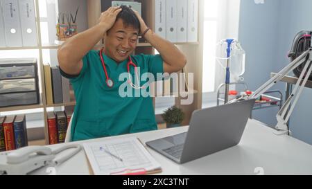 Un giovane asiatico attraente in una clinica che indossa uno stetoscopio sembra stressato mentre lavora su un computer portatile nel suo luogo di lavoro veterinario. Foto Stock