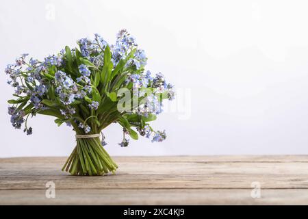 Bouquet di bellissimi fiori "dimentica" su un tavolo di legno su sfondo bianco, spazio per il testo Foto Stock
