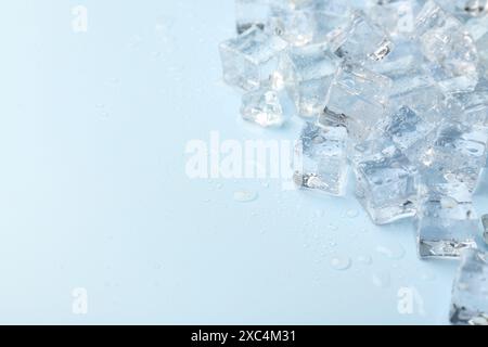 Cubetti di ghiaccio cristallini su sfondo azzurro, primo piano. Spazio per il testo Foto Stock