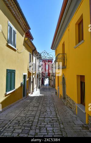 Un'affascinante strada stretta in un villaggio italiano con edifici colorati e un cielo azzurro. Foto Stock