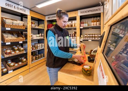 Bad Nauheim, Germania. 14 giugno 2024. Kim Rolshausen, manager del negozio self-service Hoffreunde, dimostra come eseguire la scansione e pagare le merci. Nel 2023, Hoffreunde ha aperto il container self-service di un'azienda agricola a Bad Nauheim, oltre al normale negozio di fattoria Hoffreunde a Butzbach. I clienti possono fare acquisti qui 24 ore su 24 utilizzando la propria scheda EC. I clienti troveranno una selezione di cibi regionali, che possono essere pagati alla fine dell'acquisto utilizzando il sistema di pagamento automatico. Crediti: Christian Lademann/dpa/Alamy Live News Foto Stock