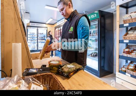 Bad Nauheim, Germania. 14 giugno 2024. Kim Rolshausen, manager del negozio self-service Hoffreunde, dimostra come eseguire la scansione e pagare le merci. Nel 2023, Hoffreunde ha aperto il container self-service di un'azienda agricola a Bad Nauheim, oltre al normale negozio di fattoria Hoffreunde a Butzbach. I clienti possono fare acquisti qui 24 ore su 24 utilizzando la propria scheda EC. I clienti troveranno una selezione di cibi regionali, che possono essere pagati alla fine dell'acquisto utilizzando il sistema di pagamento automatico. Crediti: Christian Lademann/dpa/Alamy Live News Foto Stock