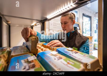 Bad Nauheim, Germania. 14 giugno 2024. Kim Rolshausen, direttore del negozio self-service Hoffreunde, controlla la merce. Nel 2023, Hoffreunde ha aperto il container self-service di un'azienda agricola a Bad Nauheim, oltre al normale negozio di fattoria Hoffreunde a Butzbach. I clienti possono fare acquisti qui 24 ore su 24 utilizzando la propria scheda EC. I clienti troveranno una selezione di cibi regionali, che possono essere pagati alla fine dell'acquisto utilizzando il sistema di pagamento automatico. Crediti: Christian Lademann/dpa/Alamy Live News Foto Stock