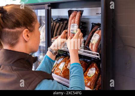 Bad Nauheim, Germania. 14 giugno 2024. Kim Rolshausen, direttore del negozio self-service Hoffreunde, controlla la merce. Nel 2023, Hoffreunde ha aperto il container self-service di un'azienda agricola a Bad Nauheim, oltre al normale negozio di fattoria Hoffreunde a Butzbach. I clienti possono fare acquisti qui 24 ore su 24 utilizzando la propria scheda EC. I clienti troveranno una selezione di cibi regionali, che possono essere pagati alla fine dell'acquisto utilizzando il sistema di pagamento automatico. Crediti: Christian Lademann/dpa/Alamy Live News Foto Stock