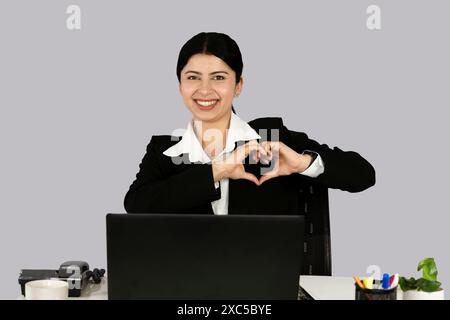 La bella recettinista asiatica indiana imprenditrice con laptop, cuffie e diario dà gesti ed espressioni Foto Stock