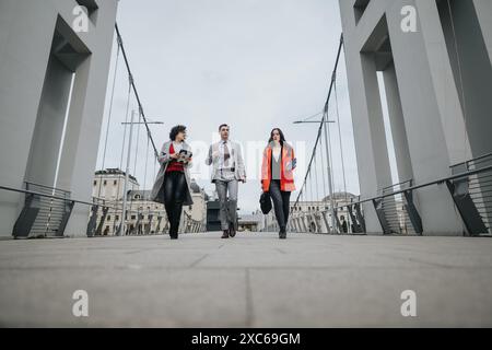 Tre avvocati si recano a piedi per una riunione di lavoro all'aperto in un ambiente urbano moderno Foto Stock