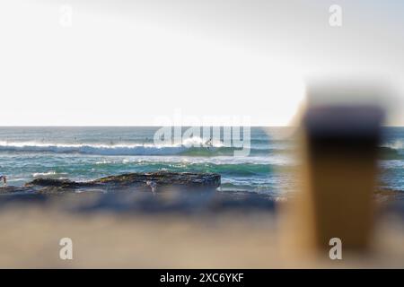 Caffè di prima mattina con spiaggia, gabbiani e surfisti sullo sfondo Foto Stock