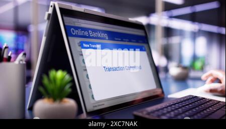 Digital Banking: Imprenditrice afroamericana che utilizza l'autenticazione mobile per il trasferimento finanziario su schermi di notebook e tablet Foto Stock