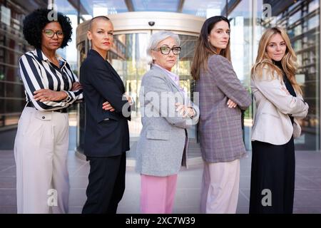 Vista laterale donne d'affari multirazziali che si pongono seriamente alla telecamera Foto Stock