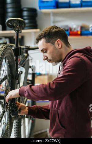 Immagine verticale delle mani di un meccanico che cambia la catena sul deragliatore posteriore di una mountain bike. Foto Stock