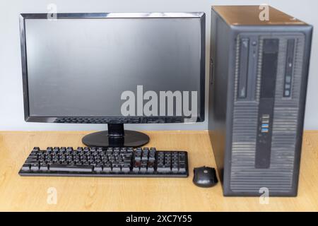 Computer desktop con monitor, tastiera e mouse su una scrivania in legno Foto Stock