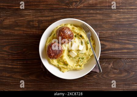 Purè di patate con cotolette di carne tritate in un recipiente bianco su sfondo di legno. Cibo sano e confortevole. Vista dall'alto, disposizione piatta Foto Stock