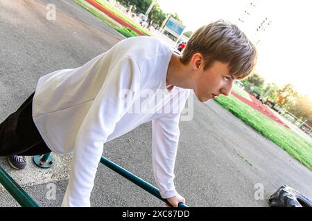 Young Man che fa un tuffo nei bar paralleli della palestra all'aperto Foto Stock