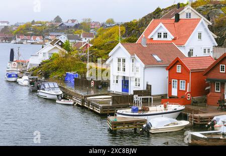 Cottage estivi rossi e bianchi sul lungomare, con barche attraccate lungo il molo e capanne estive sul mare sull'isola di Flekkeroya. Kristiansand, Norw Foto Stock