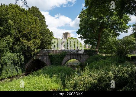 Ponte ad arco in pietra sul fiume skell con torre dell'Abbazia delle Fontane sullo sfondo. Ripon, North Yorkshire, Inghilterra, Regno Unito. Foto Stock