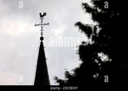Ein Kreuz mit Wetterhahn steht auf dem Dach einer Kirche vor Wolkenhimmel Der Kirchenaustritt ist die vom Bürger auf eigenen Wunsch veranlasste Beendigung der staatlich registrierten Mitgliedschaft in einer Kirche. Themenbild, Symbolbild Frechen, 14.05.2024 NRW Deutschland *** Una croce con un rubinetto si erge sul tetto di una chiesa di fronte a un cielo nuvoloso che lascia la chiesa è la cessazione dell'appartenenza statale a una chiesa su richiesta dei cittadini immagine a tema, immagine simbolica Frechen, 14 05 2024 NRW Germania Copyright: xChristophxHardtx Foto Stock