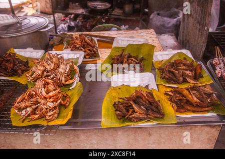 granchi al barbecue e pesce fritto, esposti su foglie di banana, in vendita in una banchina all'aperto. Il mercato del granchio, KEP, Cambogia. © Kraig Lieb Foto Stock