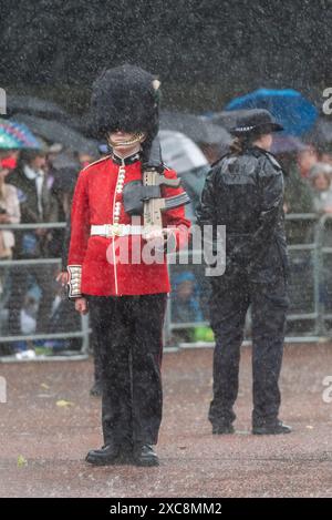 The Mall, Westminster, Londra, Regno Unito. 15 giugno 2024. La famiglia reale, le bande e le truppe in massa sono tornate al Mall dalla Horse Guards Parade per la cerimonia del Trooping of the Colour, nota anche come King's Birthday Parade. Street Liner e la polizia si bagnano molto durante un temporale Foto Stock