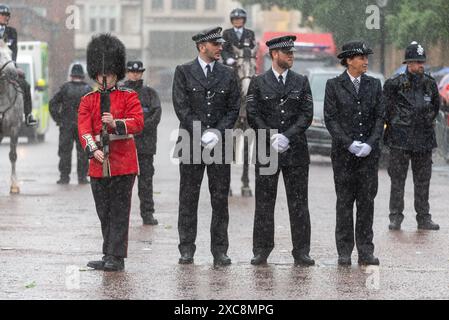 The Mall, Westminster, Londra, Regno Unito. 15 giugno 2024. La famiglia reale, le bande e le truppe in massa sono tornate al Mall dalla Horse Guards Parade per la cerimonia del Trooping of the Colour, nota anche come King's Birthday Parade. Street Liner e la polizia si bagnano molto durante un temporale Foto Stock