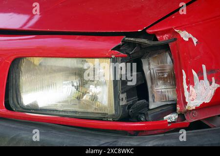 Primo piano del danno in prossimità del faro - un indicatore di direzione rotto, graffi e ammaccature sul parafango. Dopo una collisione con un'auto. Foto Stock