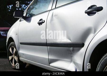 Foto di un'autovettura argentata con una grave ammaccatura sulla portiera posteriore. Un'auto con danni materiali dopo una collisione stradale. Foto Stock