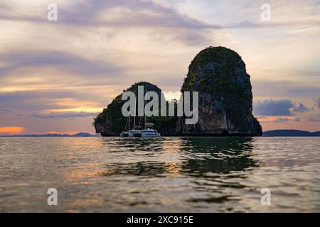 Tramonto dietro l'isolotto carsico calcareo di Ko Rang NOK coperto di foresta pluviale visto dalla spiaggia della grotta di Phra Nang sulla penisola di Railay nella provincia di Foto Stock