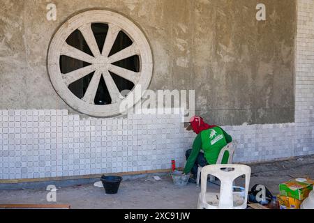 Operaio thailandese che piastrella un muro esterno del grande Buddha di Phuket, che lo ricopre con piastrelle di marmo birmano bianco sull'isola di Phuket, Thailandia Foto Stock