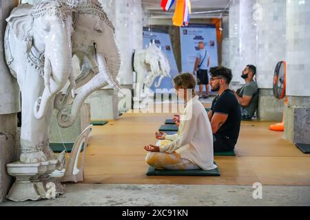 Turisti caucasici che meditano all'interno del grande Buddha di Phuket, alias Ming Mongkol Buddha, una statua di Buddha Maravijaya seduta in cemento Foto Stock