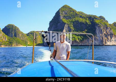 Guida sorridente locale che guida una barca a coda lunga fuori dalla baia di Maya sull'isola di Koh Phi Phi Ley nel Mare delle Andamane, provincia di Krabi, Thailandia Foto Stock