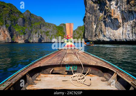 Barca a coda lunga che naviga attraverso alcune scogliere carsiche spettacolari sull'isola di Koh Phi Phi Ley nel Mare delle Andamane, nella provincia di Krabi, Thailandia Foto Stock