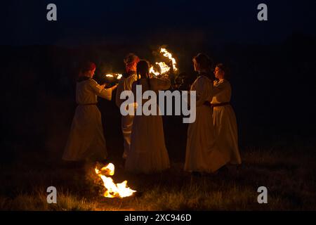 REGIONE DI TVER, RUSSIA - 21 LUGLIO 2023: Le ragazze in abiti bianchi illuminano un fuoco in una notte buia. Festival storico "Epic Coast-2023" Foto Stock