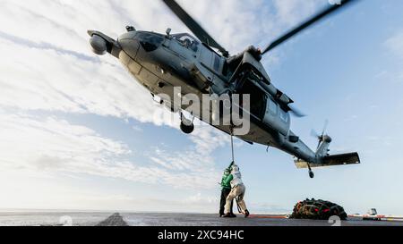 Un MH-60S Seahawk, assegnato all'Helicopter Sea Combat Squadron (HSC) 5, raccoglie le reti dal ponte di volo durante un rifornimento verticale a bordo della Nimit Foto Stock