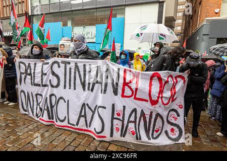 Manchester, Regno Unito. 15 giugno 2024. Sangue palestinese sulle bandiere delle mani di Barclays alle proteste di guerra in Palestina a Gaza a Manchester nel Regno Unito durante le forti piogge. I manifestanti hanno marciato da Piazza San Pietro attraverso il centro della città. Gli striscioni includevano messaggi che chiedevano a Israele di liberare i prigionieri politici palestinesi e criticavano la Barclays Bank. Crediti: GaryRobertsphotography/Alamy Live News Foto Stock