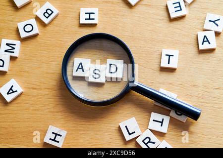 Lente di ingrandimento posizionata sulle lettere ASD autismo disturbo dello spettro Foto Stock